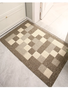 Close-up detail of geometric block patterns and looped texture on brown entryway doormat