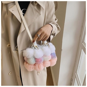 Detail of colorful plush pom-pom handbag with metal handles and slim shoulder strap