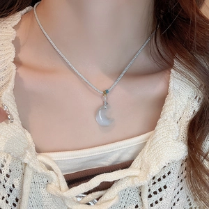 Macro detail of crescent moon pendant with opal-like stone on silver cord necklace
