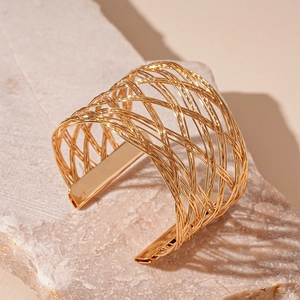 Minimalist gold woven mesh open cuff bracelet displayed on a natural stone base