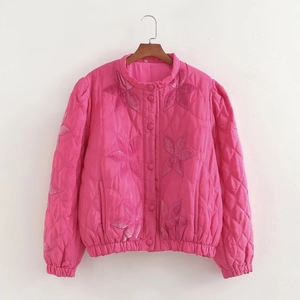 Detailed close-up of quilted pink jacket with floral embroidery and fabric buttons