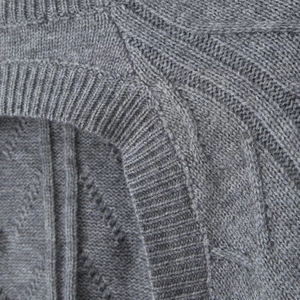 Macro detail of soft grey knitted fabric texture and fine stitching on the shoulder seam