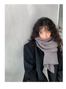 Detail of grey pleated knit scarf texture paired with a black blazer for urban style