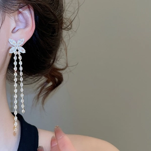 Macro side view of silver butterfly tassel earrings with sparkling zircon stones on a model