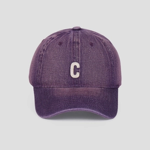 Detailed shot of white embroidered C letter on washed purple denim baseball cap