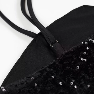Close-up of black sequin embroidery detail with thin shoulder straps and metal rings