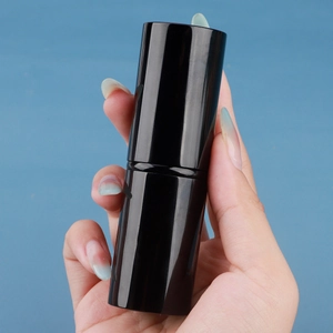 Handheld view of retractable cat paw makeup brush in a sleek glossy black cylindrical case