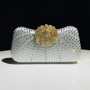 Detailed close-up of sparkling silver rhinestones and gold floral clasp on luxury evening clutch