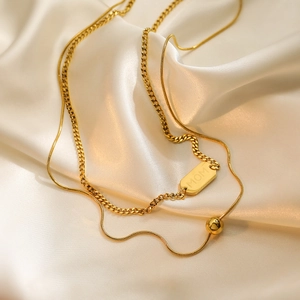 Gold layered necklace with Cuban link MOM pendant and snake chain on white silk