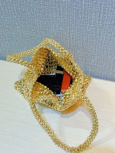 Close-up of golden beaded handbag showing spacious interior with cosmetic items inside