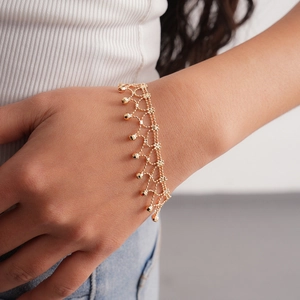 Detailed macro view of a gold woven mesh bracelet with polished hanging beads on wrist