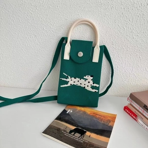 Close-up of green knit phone bag featuring a pixelated dog pattern and white top handle