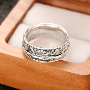 Detailed close-up of retro silver mountain range relief ring on a wooden jewelry box