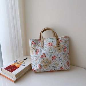 Vue détaillée du sac cabas en toile à fleurs avec poignées en cuir marron et rivets
