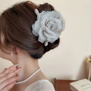Détail d'une pince à cheveux rose en tissu gris avec perles sur un chignon