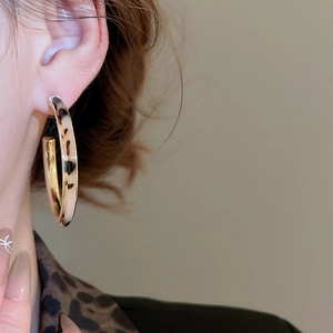 Detail view of large C-shaped leopard print earrings with gold metal inner lining