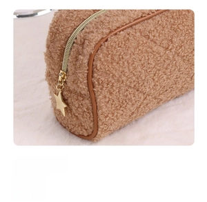Close-up of teddy fleece makeup bag with brown leather piping and star zipper pull