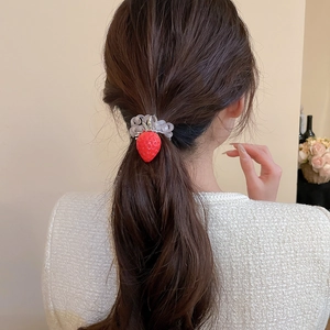 Détail d'un élastique à cheveux fraise rouge avec spirale sur une queue