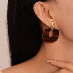 Détail d'une boucle d'oreille en résine léopard et clou doré portée par un modèle