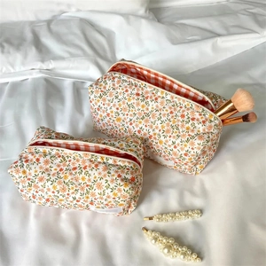 Detail of floral cotton makeup bags with checkered lining and pearl hair clip accessory