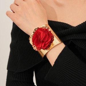 Bracelet manchette doré tendance avec une grande fleur en tissu rouge porté par un mannequin