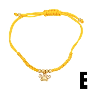 Detail of yellow woven rope bracelet with gold crab charm and sparkling zircon stones
