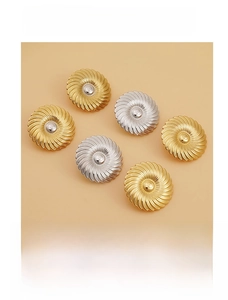 Dettaglio di orecchini a bottone rotondi con texture a spirale color oro e argento