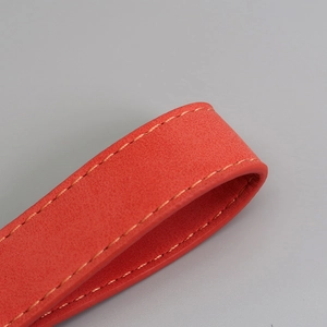 Macro shot of red suede leather strap featuring detailed yellow stitching for keychains