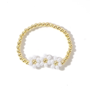 Handmade woven daisy ring with three white flowers and gold beads on white background