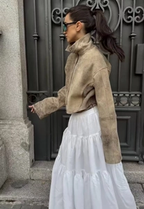 Scatto all'aperto di una giacca marrone vintage vissuta con gonna bianca a balze