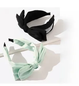 Close-up of black and mint green bow headbands with lace detail on white podium