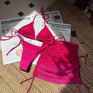 Detailed flat lay of pink 3D wave textured bikini set with matching mesh beach skirt
