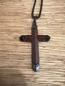 Vue macro détaillée du pendentif croix vintage en bois sombre et métal noir brossé