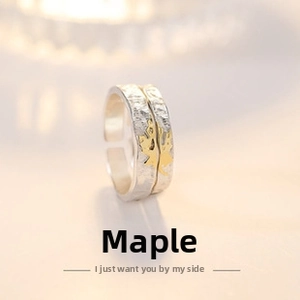 Detail of adjustable silver couple rings with hammered texture and golden maple leaf