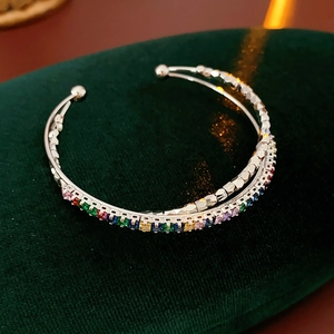 Macro shot of silver-tone crossover cuff with colorful cubic zirconia on velvet