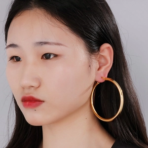 Detailed view of large 18K gold plated thick hoop earring worn by a model