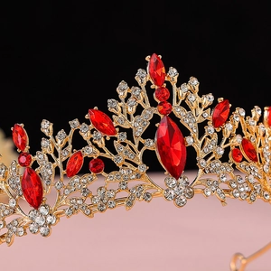 Detailed close-up of golden crown featuring red marquise gems and white rhinestones