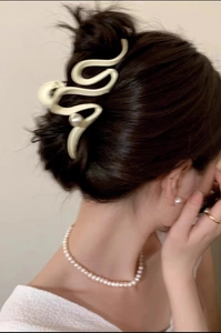 Detail view of a beige wavy hair claw clip with pearl accents on a bun hairstyle