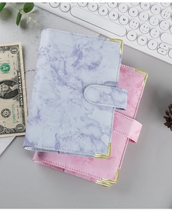 Detail of pink and purple marble PU leather notebooks with golden corners and magnetic clasp