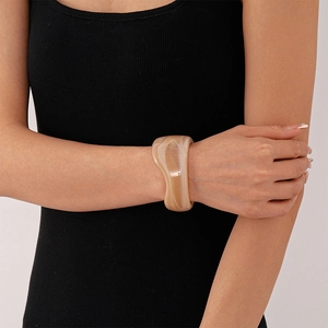 Detail of wide resin bangle with beige marble texture and wavy irregular design