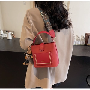 Close-up of red PU leather bag featuring gold rivets and ethnic jacquard wide strap