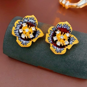 Detail of vintage flower earrings with blue enamel, gold petals, and sparkly rhinestones