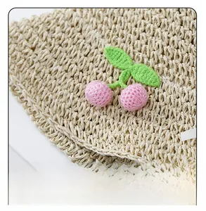 Close-up of hand-woven straw hat texture featuring delicate crochet cherry decorations