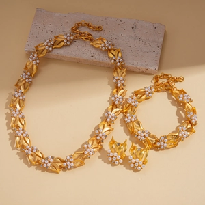 Vintage golden leaf jewelry set with pearls and rhinestones on stone background