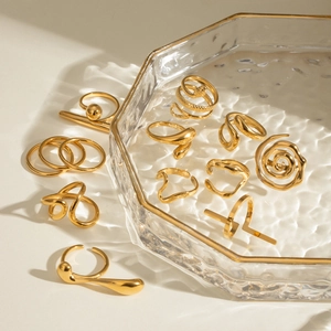 Set of minimalist gold titanium steel rings with snake and geometric designs on glass tray