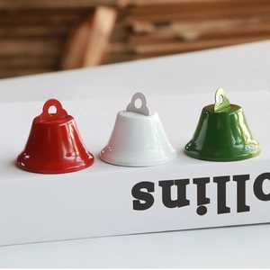 Three colorful Christmas metal bell ornaments in red white and green on a book