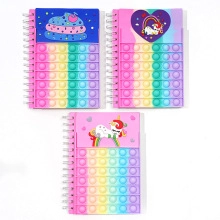 Detail of spiral notebooks featuring rainbow silicone pop-it covers and unicorn patterns