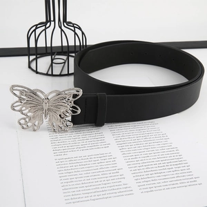 Close-up of vintage black leather belt with silver butterfly buckle on white paper