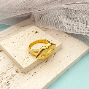 Polished 14K gold plated titanium steel lip shaped hollow ring on a stone display