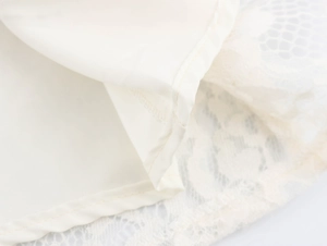Detail of elegant beige lace dress hem showing high-quality stitching and smooth lining